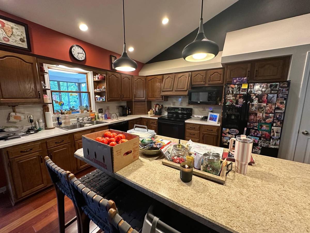 A warm, lived-in kitchen with wooden cabinets, granite countertops, and a refrigerator covered in family photos.