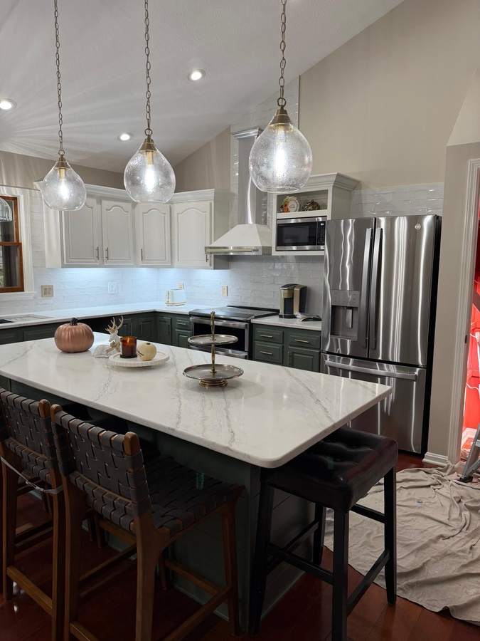 A contemporary kitchen featuring a large marble island, stainless steel appliances, and pendant lighting.
